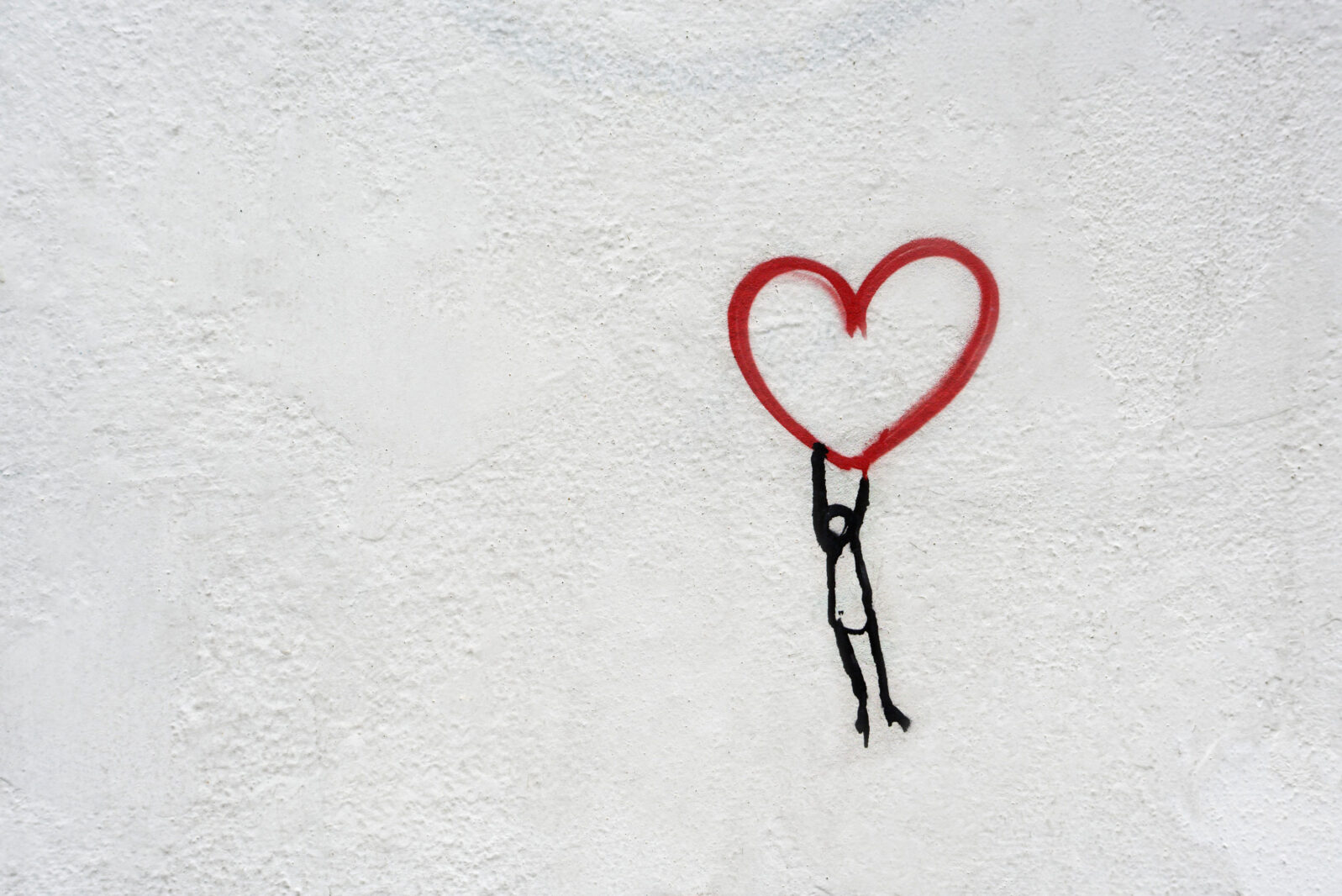 Hanging from a heart, graffiti on white wall