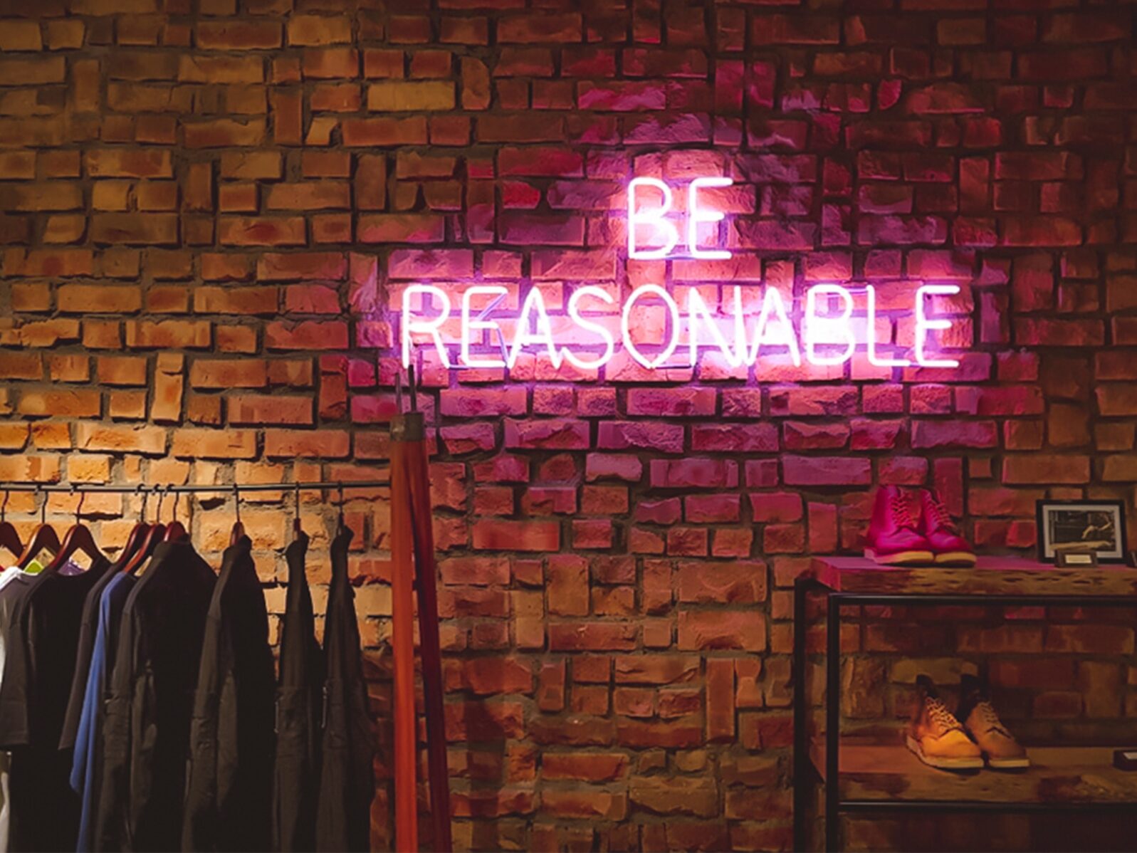 Be Reasonable written in neon on a brick wall