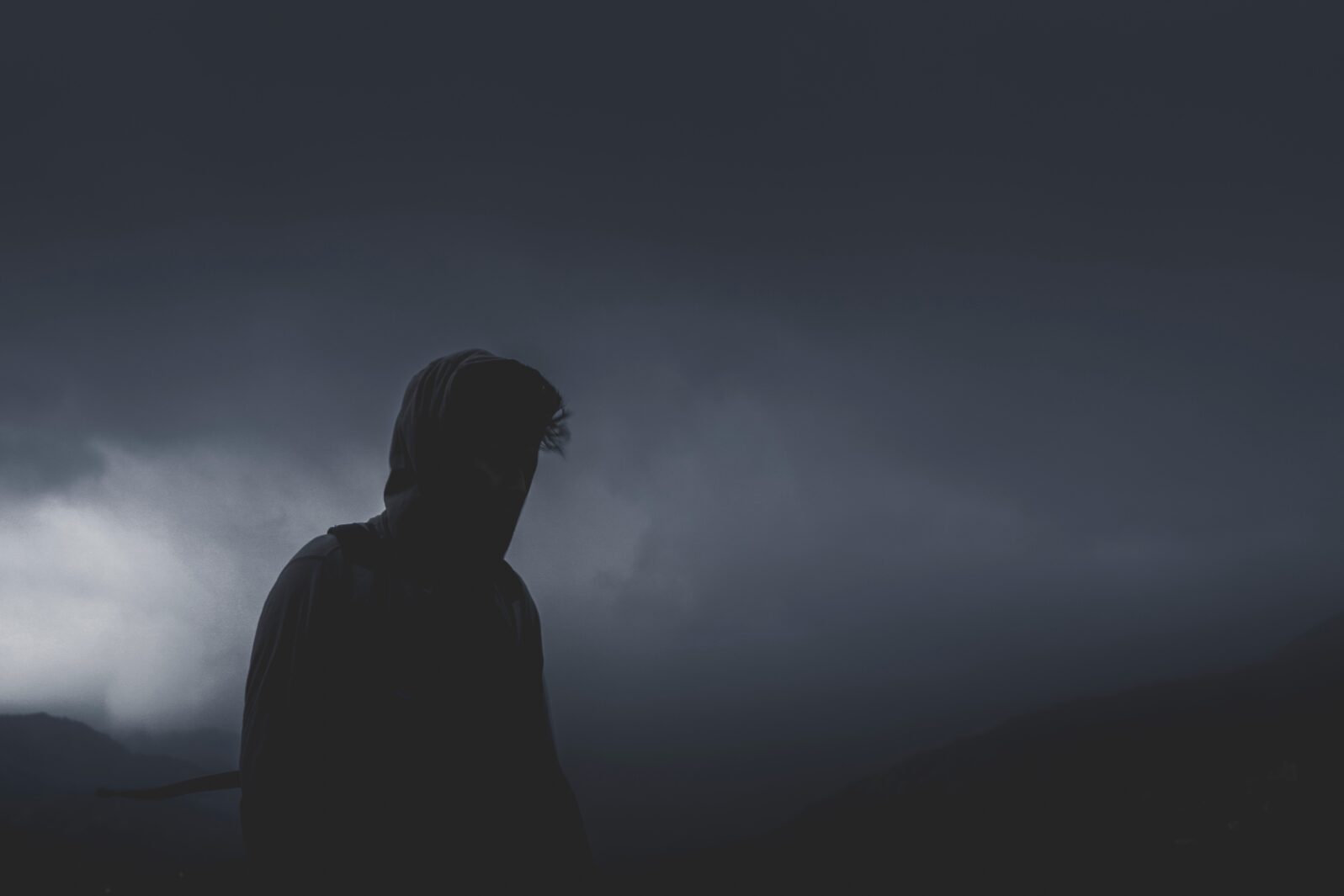 Silhouette of a man against a dark, cloudy sky