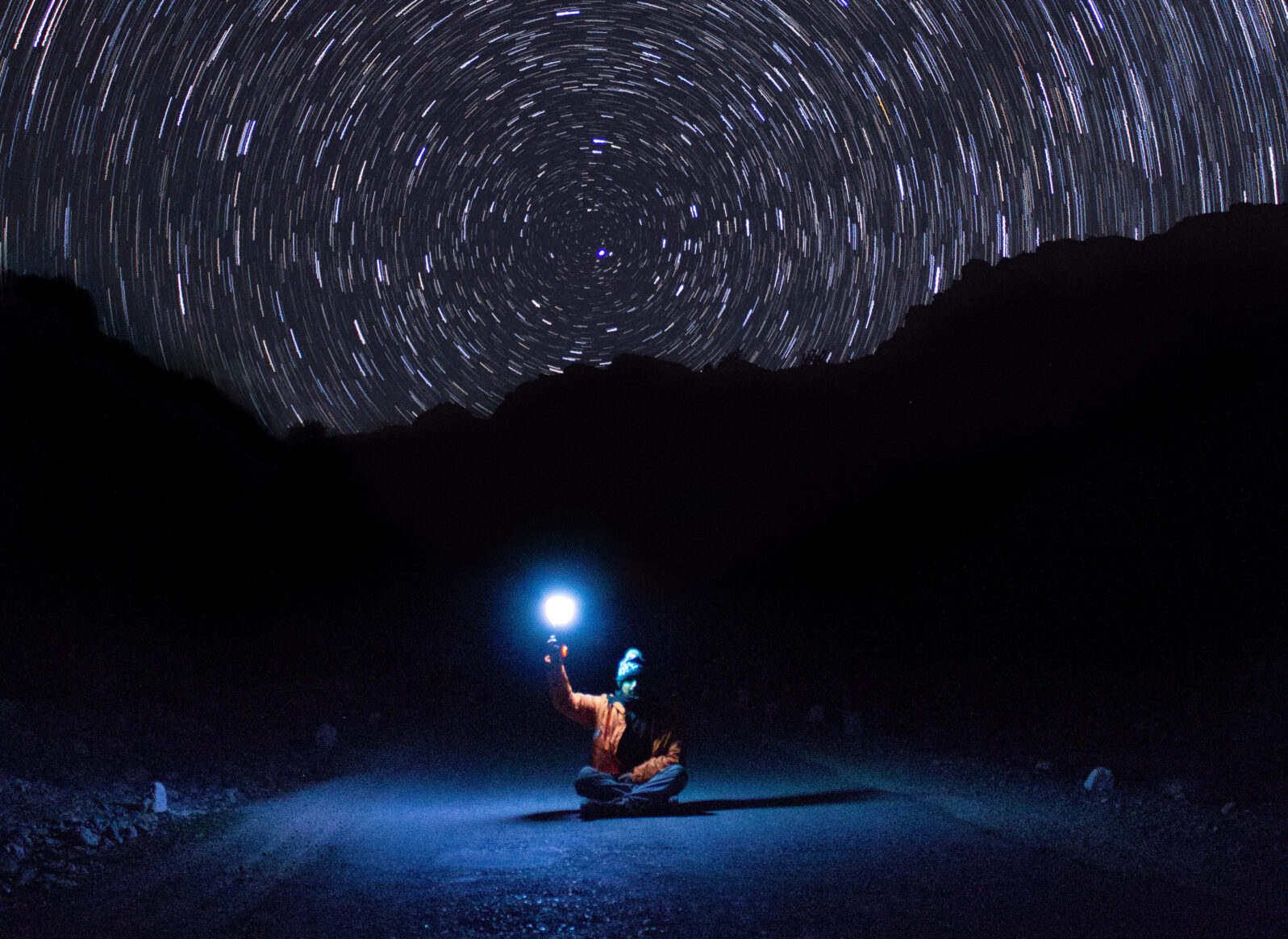 Person on road with light looking at the stars