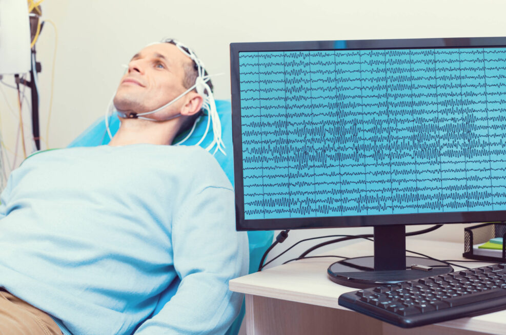 Selective focus on a computer recording brain waves of a mature gentleman getting his brain analyzed by an electroencephalography machine.
