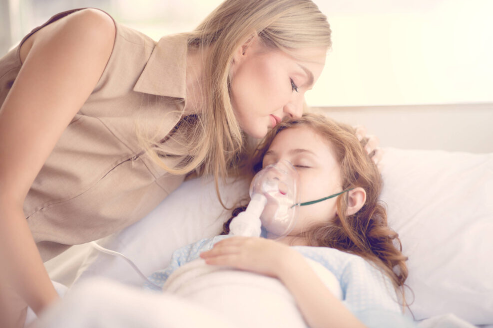 Sick girl lying on the hospital bed and her mom kiss to support.