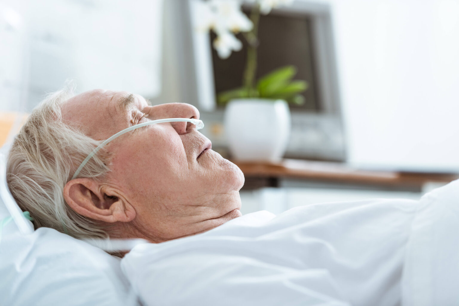 side view of senior man in coma on bed in hospital