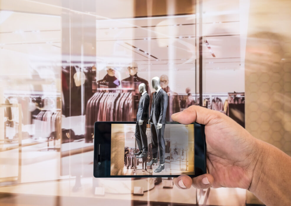 Augmented reality application for retail business concept. Hand holding smart phone with A/R application on screen to finding interested product in the store.
