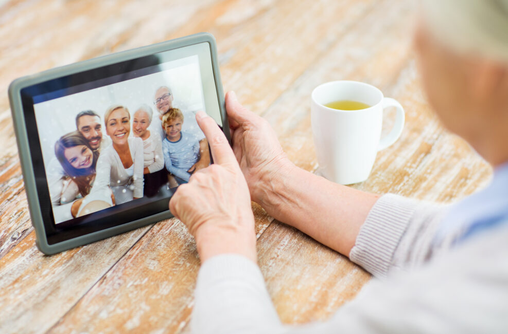 senior woman with family photo on tablet pc screen