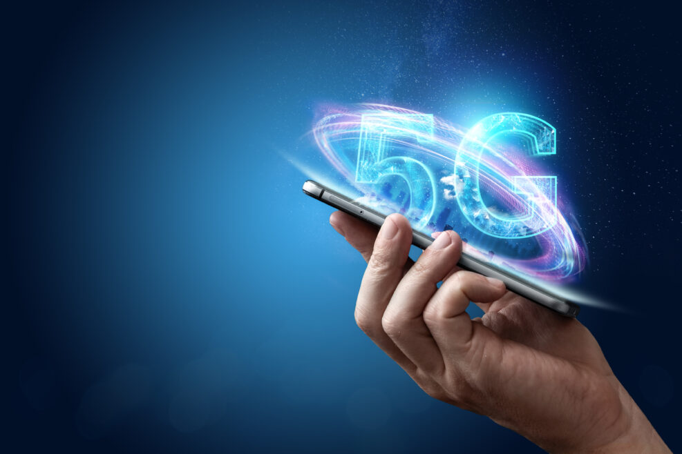 Creative background, male hand holding a phone with a 5G hologram on the background of the city. The concept of 5G network, high-speed mobile Internet, new generation networks. Copy space,