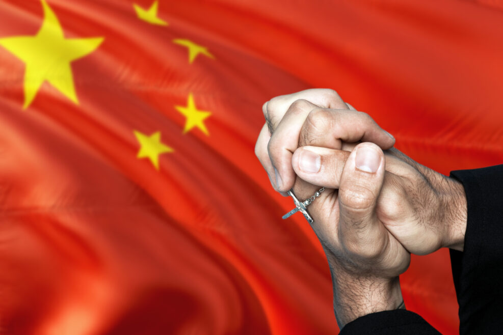 China flag and praying patriot man with crossed hands. Holding cross, hoping and wishing.