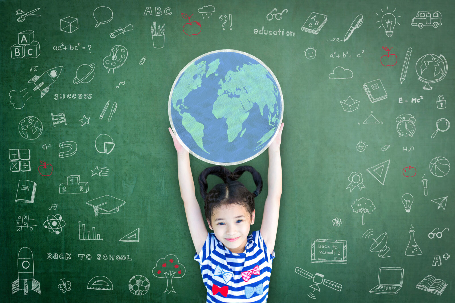 Educated school kid lifting world globe chalk doodle drawing on green chalkboard for education concept