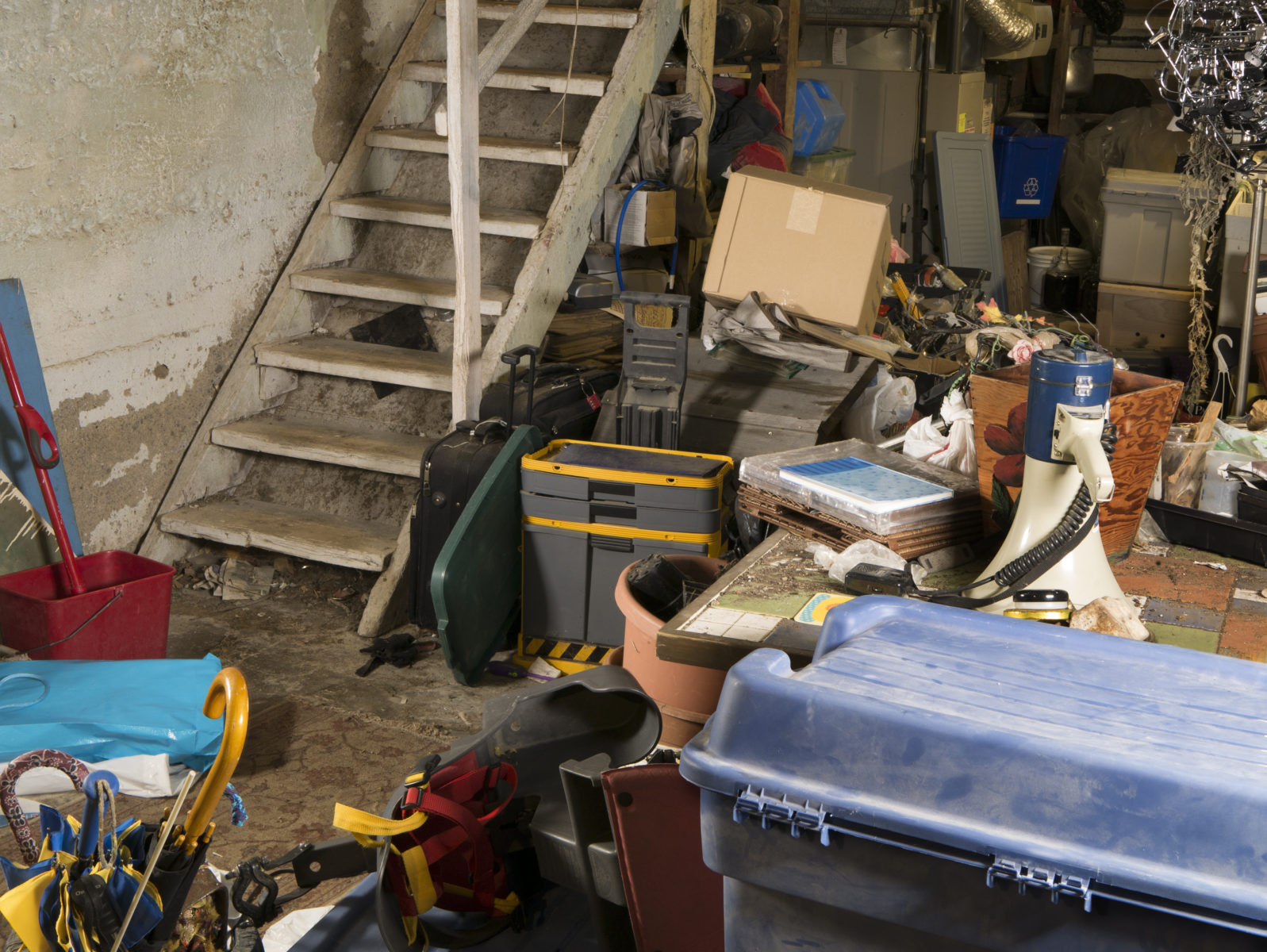 Old dingy residential unfinished basement cluttered with storage of random things