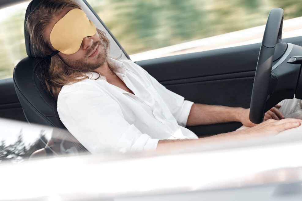 Tired man sitting in car, wearing in sleeping mask