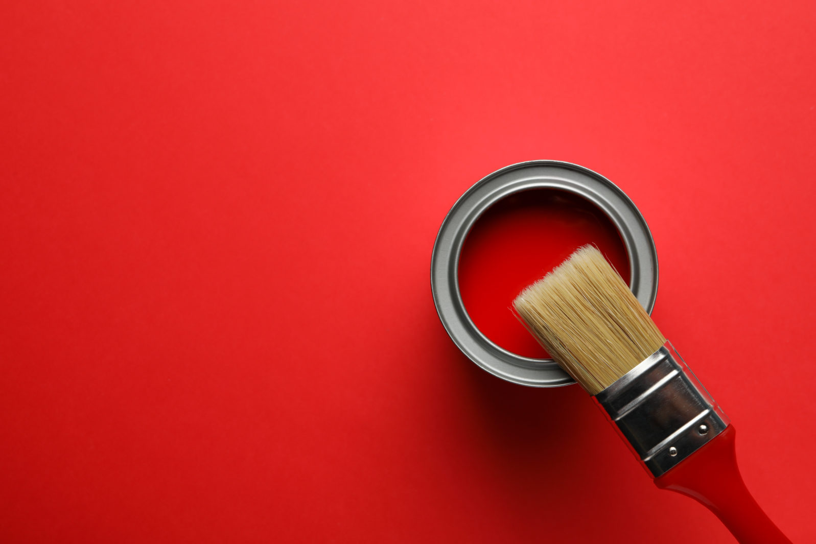 Paint can and brush on red background, top view