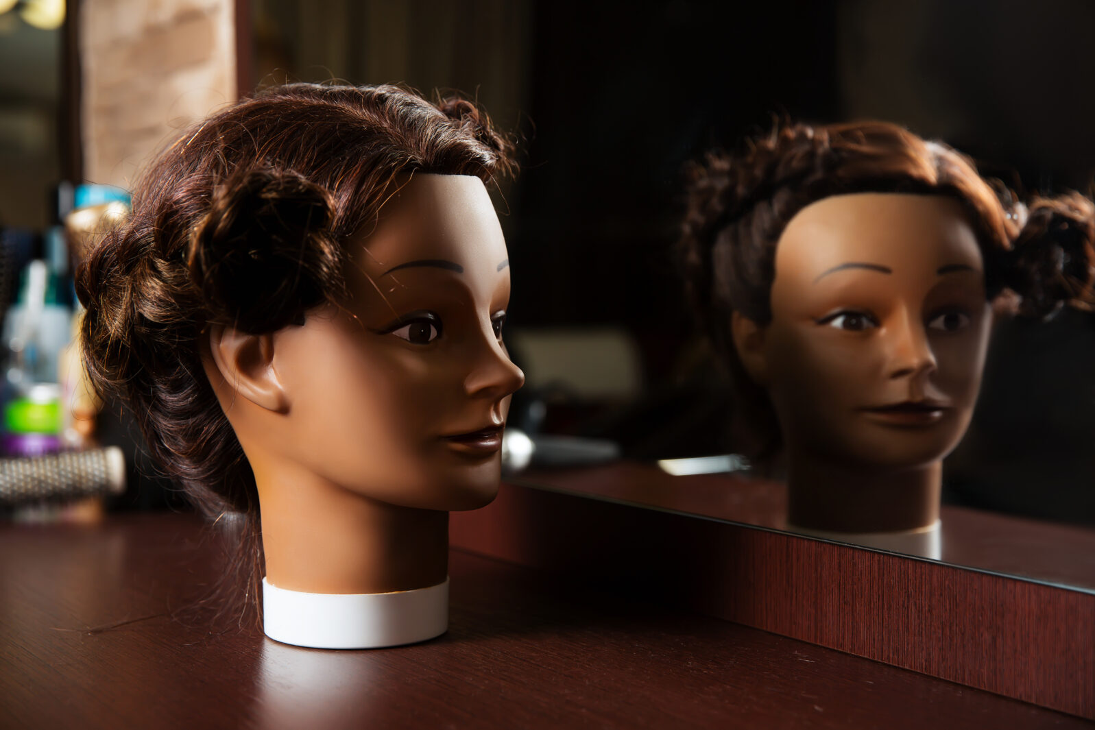 Hairdressing mannequin located on a wooden table.