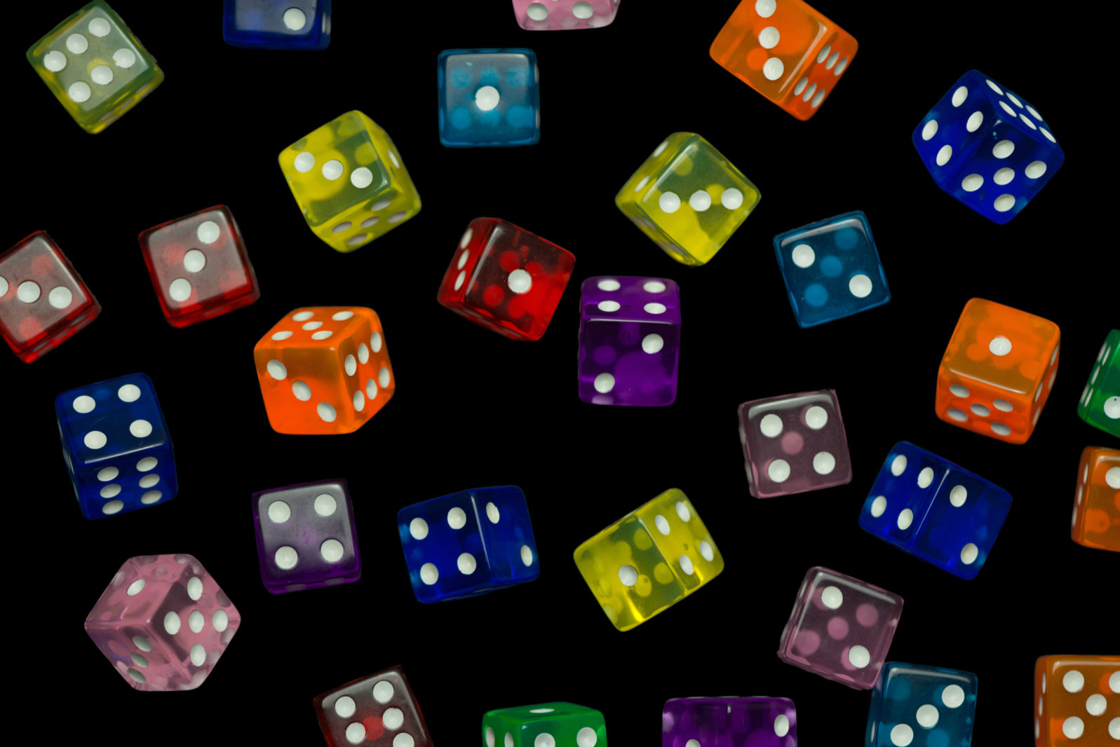 many falling translucent  multicolored  dices with white dots on black background