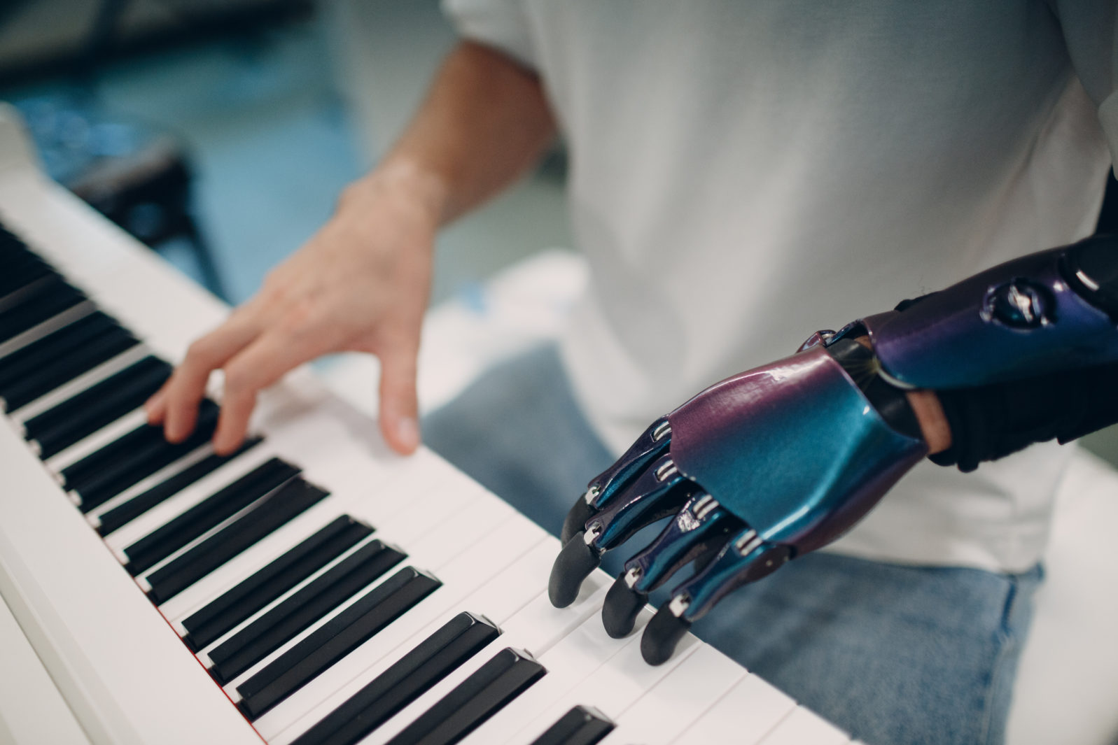 Young disabled man playing on piano electronic synthesizer with artificial prosthetic hand in music shop