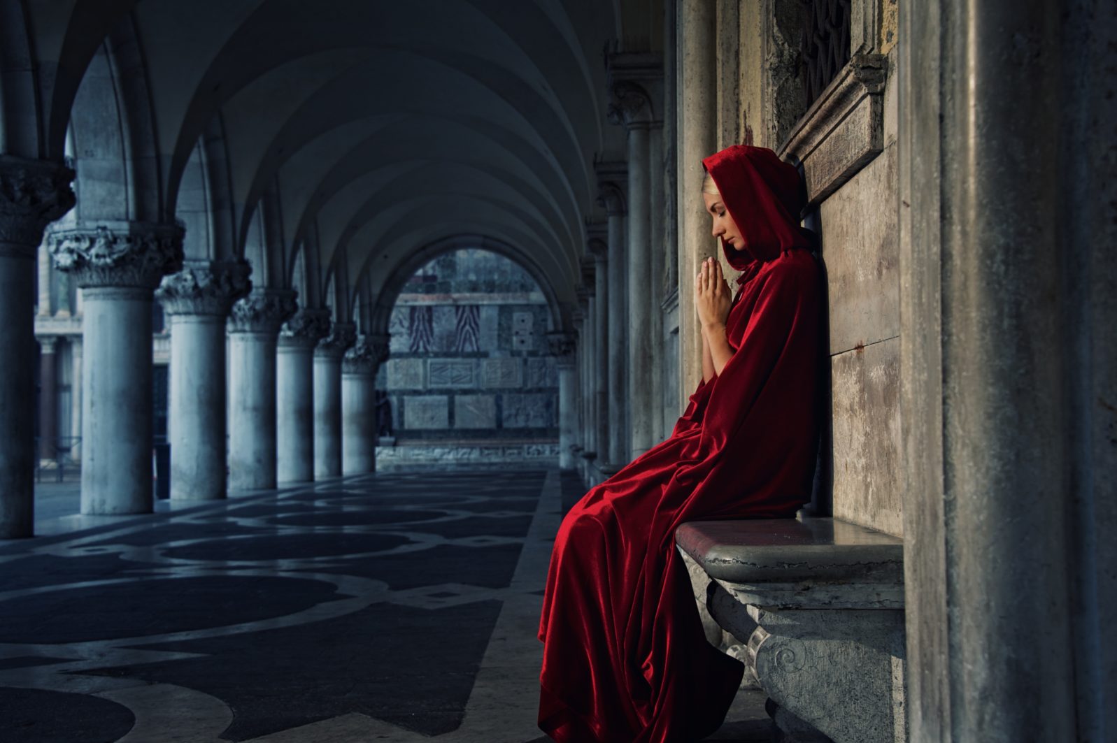 Woman in red cloak praying alone