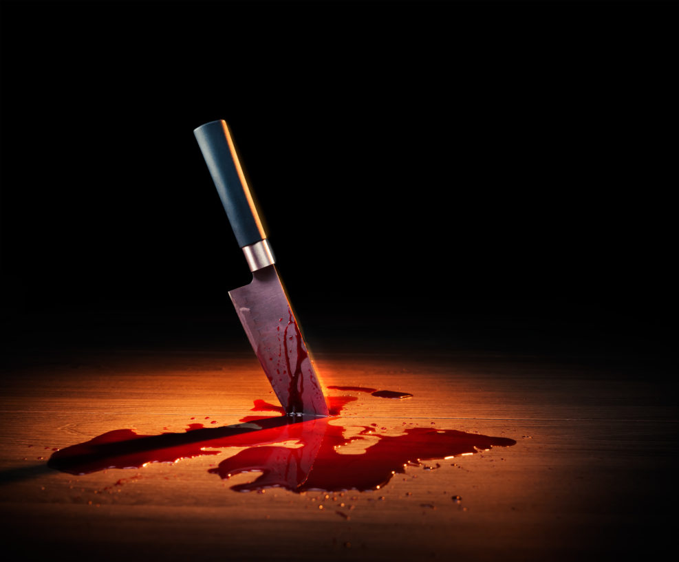 dramatic lit image of a bloody crime scene with a knife on the floor