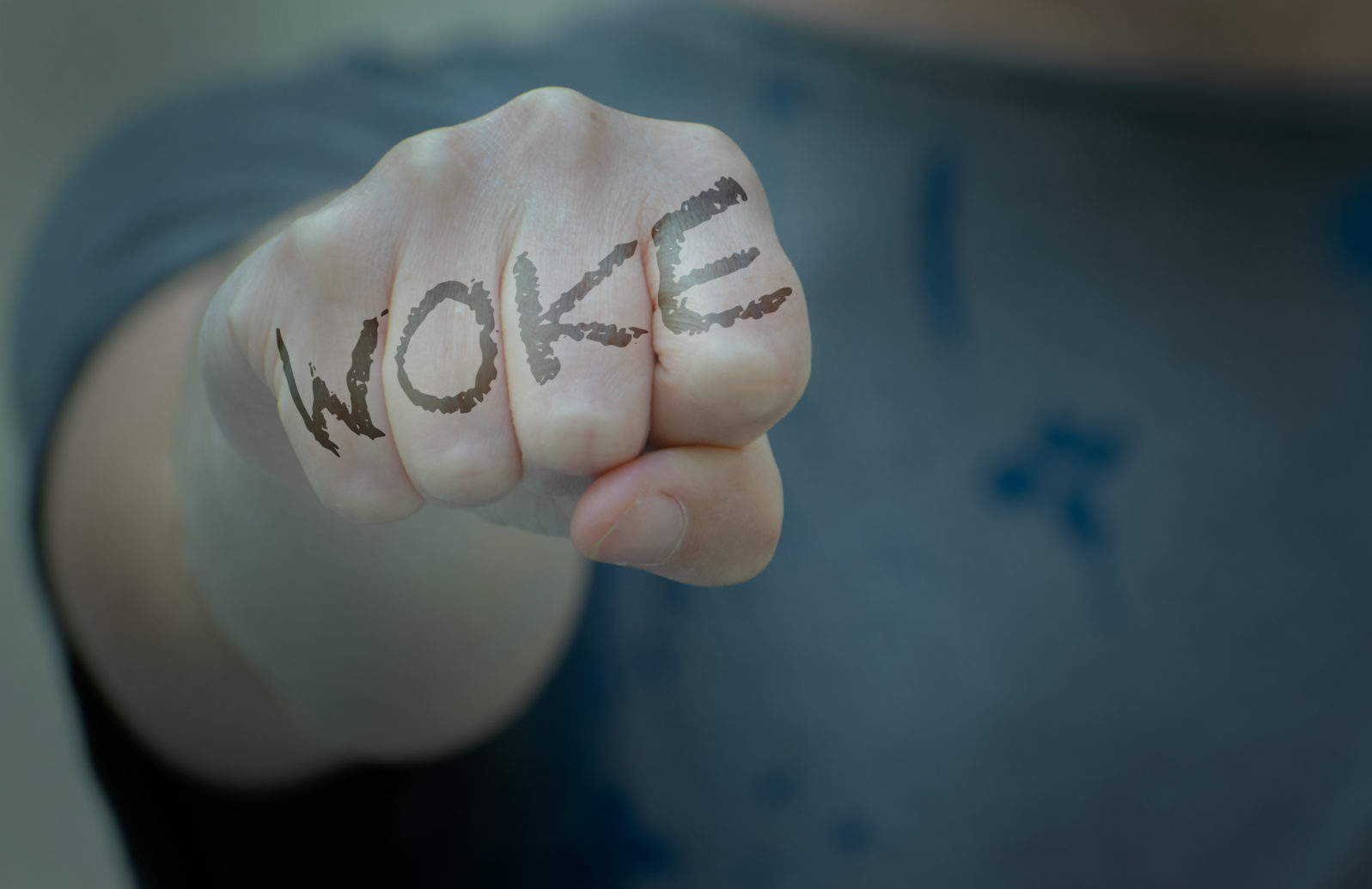 Woman fist with woke written. Woke concept refers to awareness of social and racial justice, concern, vigilance, activism.