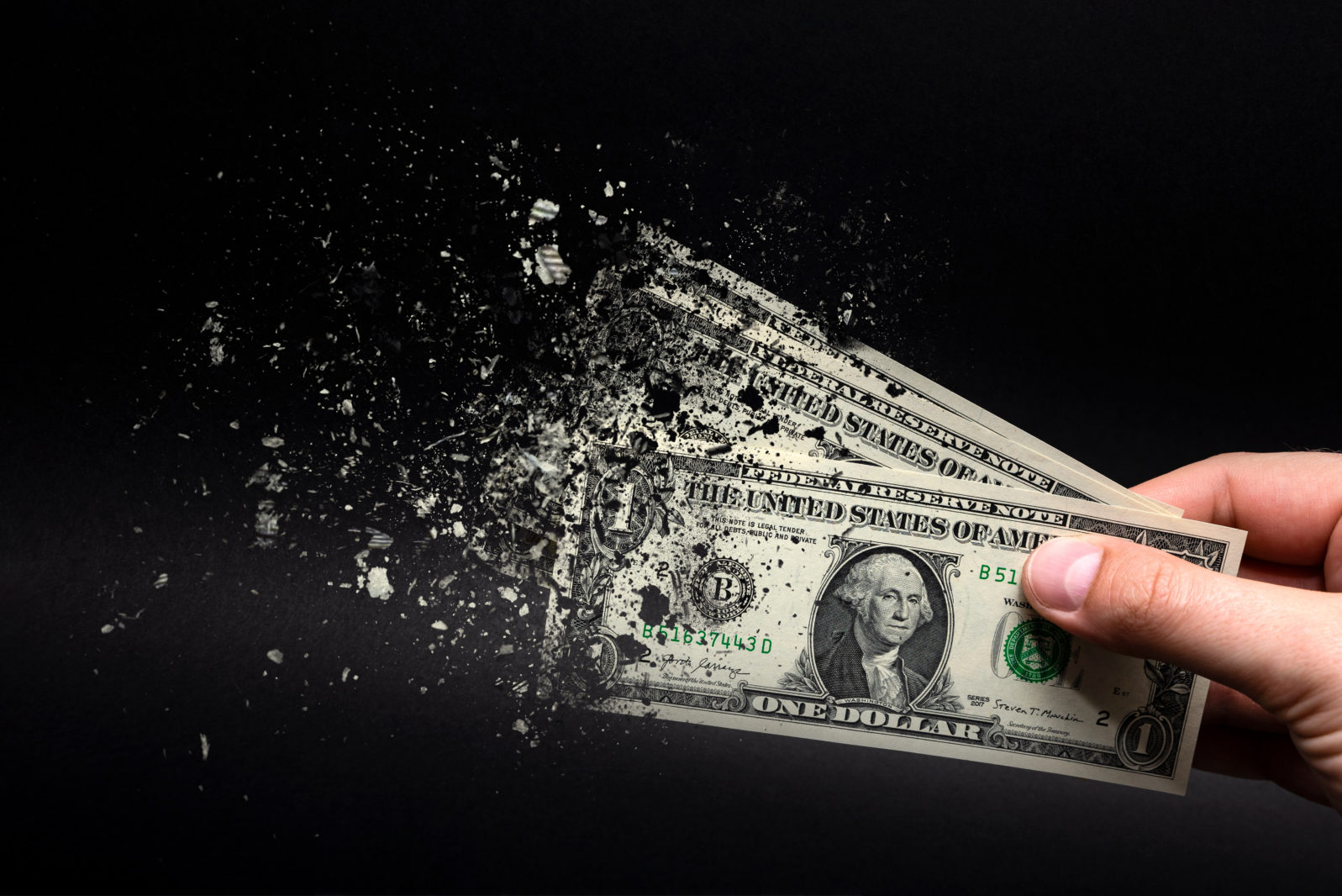 Inflation, dollar hyperinflation with black background. One dollar bill is sprayed in the hand of a man on a black background. The concept of decreasing purchasing power, inflation.