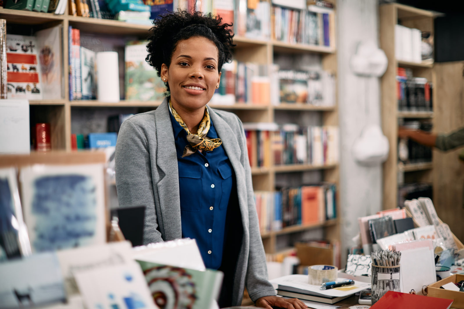 Portrait of happy black woman working in bookstore and looking at camera.