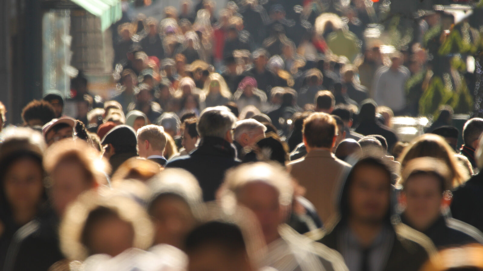 Crowd of people walking busy New York City street backlit