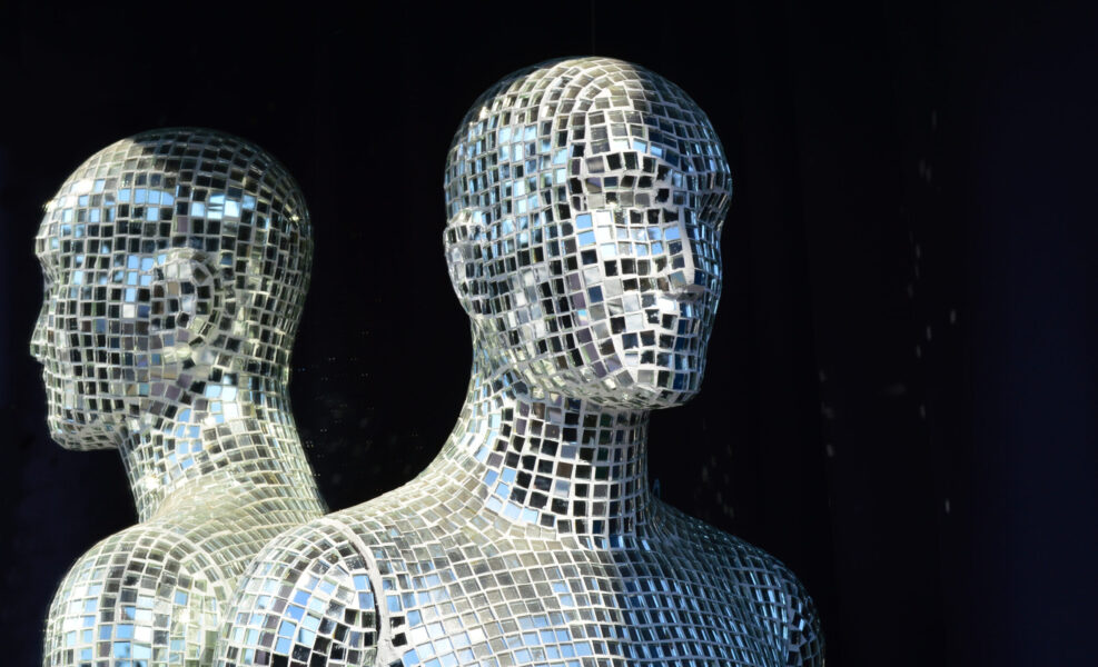 Male mannequin covered with slices of a mirror on a black background
