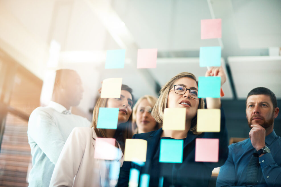 Planning, innovation and vision business meeting in a modern office, working on a business marketing strategy. Group, team or staff discussing with sticky notes a schedule for future project together