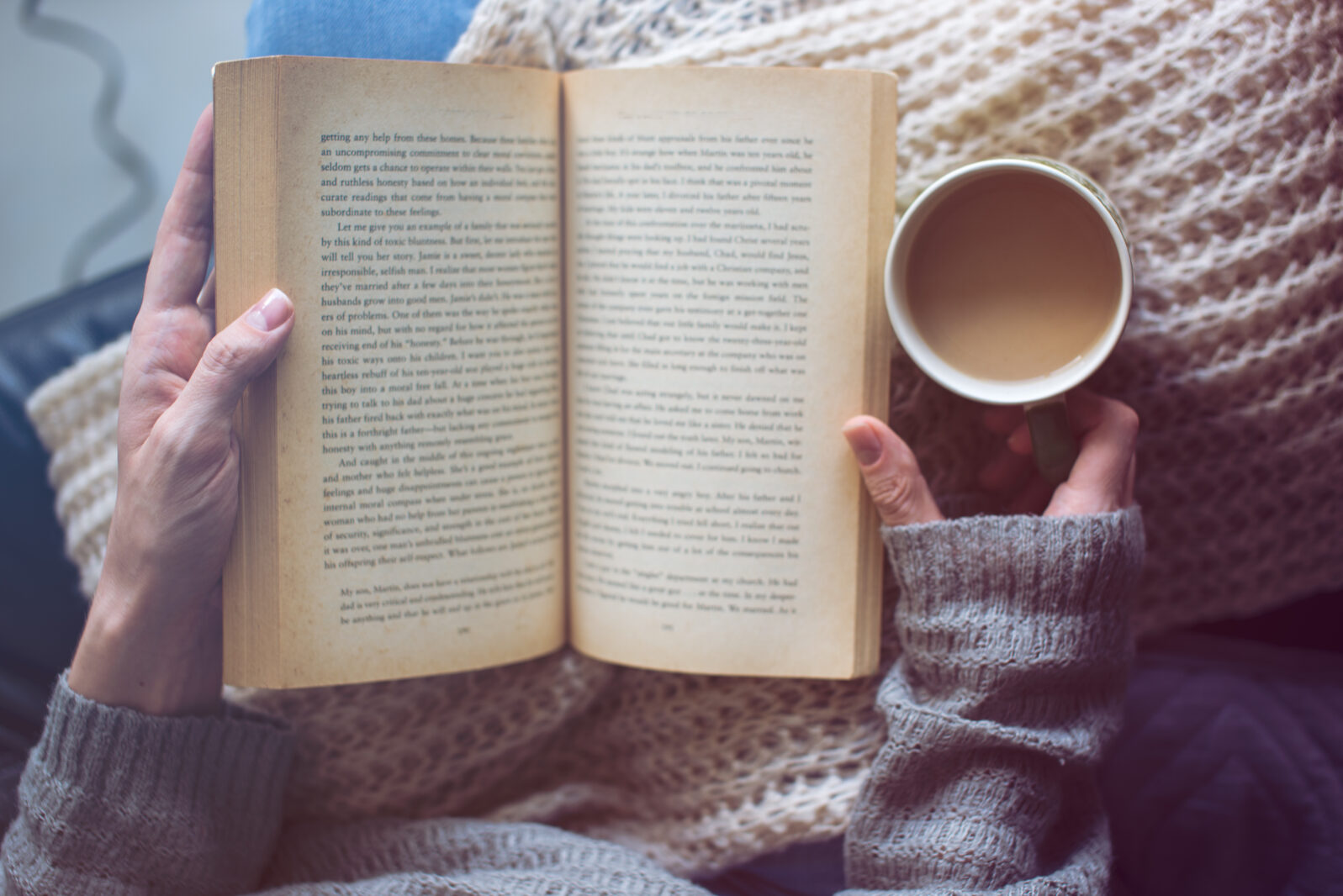 a woman is reading a book and holding coffee