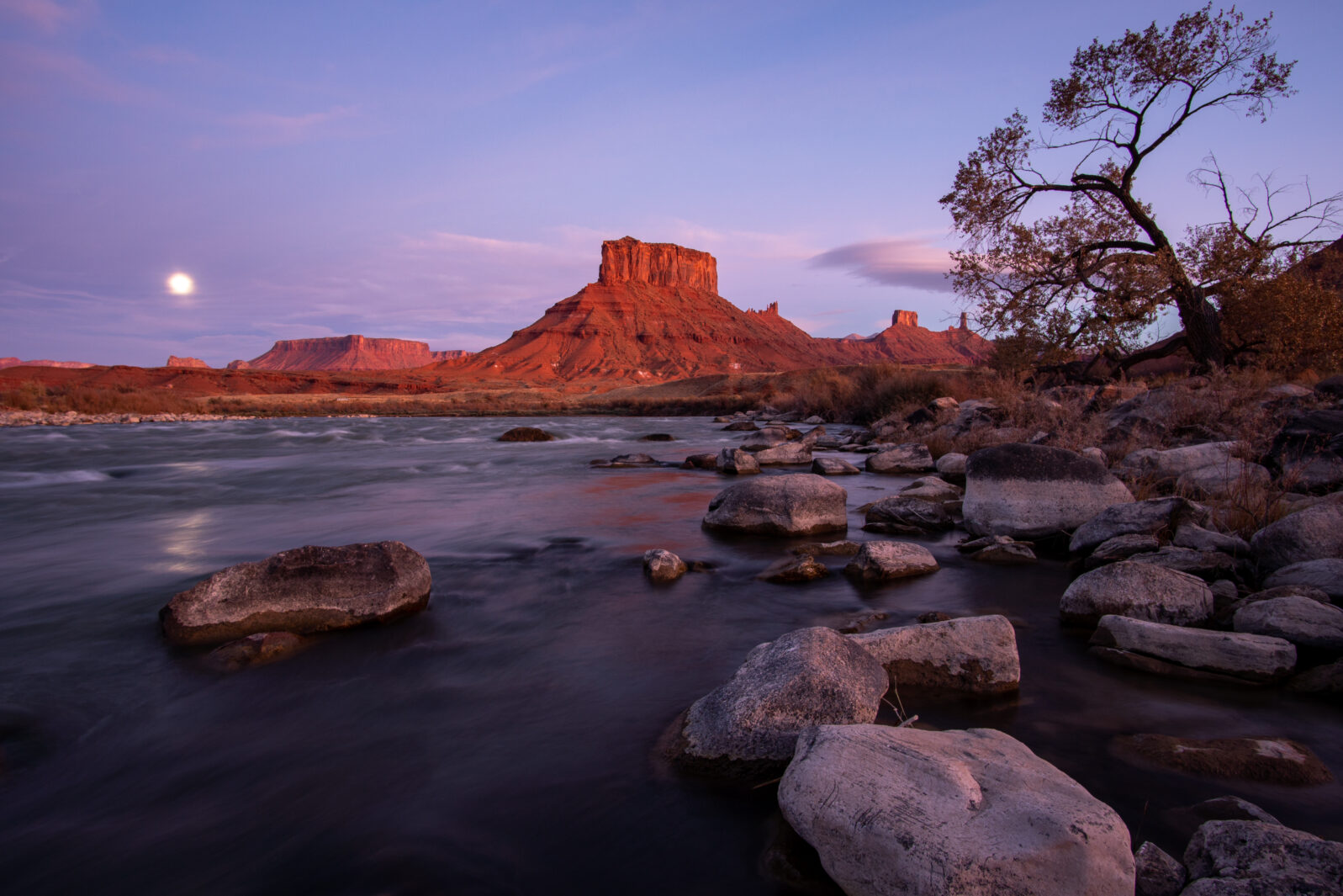 Colorado river with desert landscape glowing in Utah near moab with moon