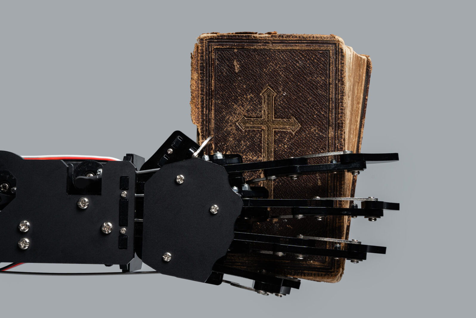 Real robot's hand with ancient Bible. Concepts of artificial intelligence development and machine learning