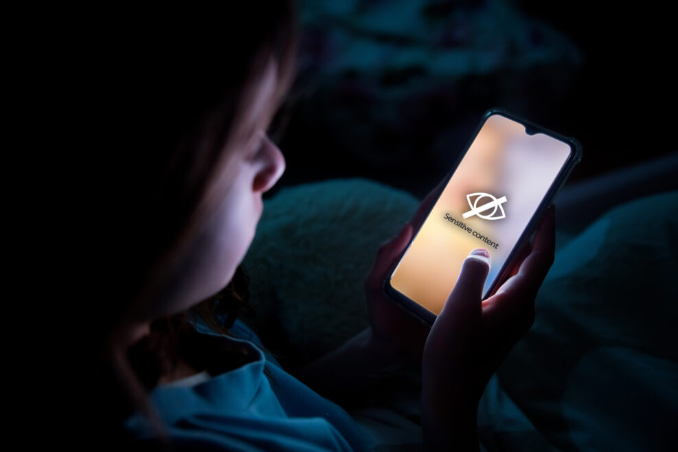 A child using smart phone lying in bed late at night, playing games. Children's screen addiction and parent control concept. Child's room at night. Sensitive content on screen