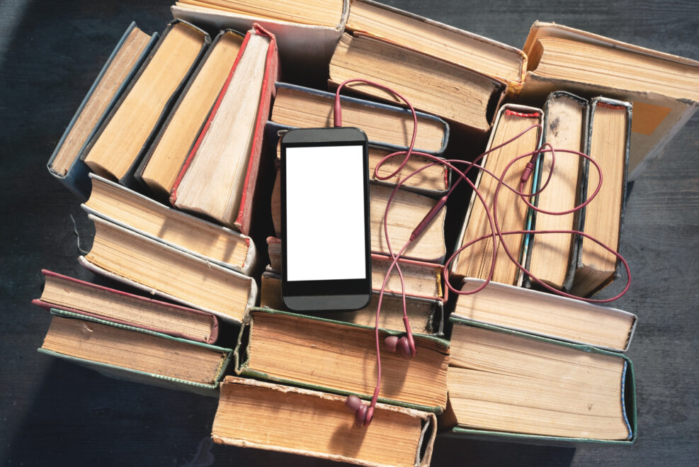 Mobile phone with blank screen with copy space and old books. Electronic book concept.