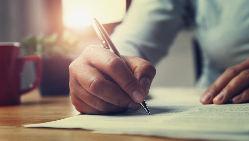 hand of woman holding pen with writing on paper report in office