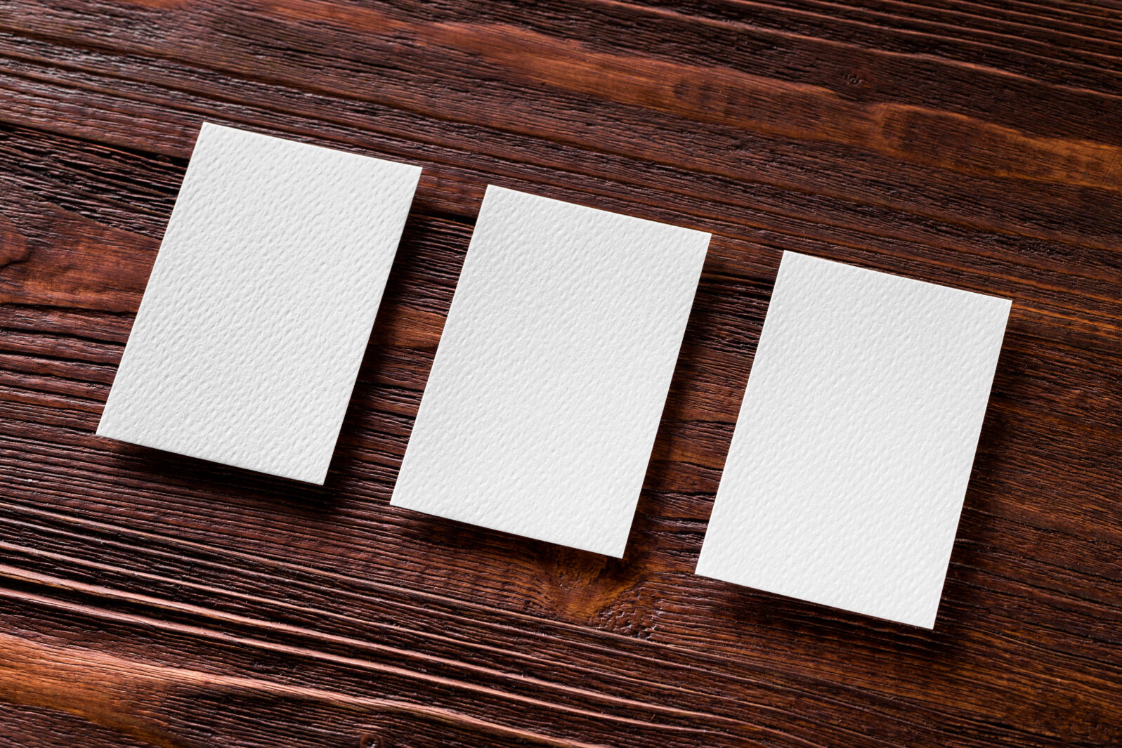 Closeup mockup of three blank vertical business cards at brown w