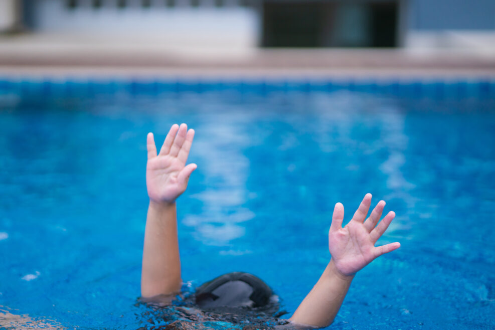 child in danger drowning in the pool, kid girl cannot swim to deep water and raise two hand for help on swimming pool.