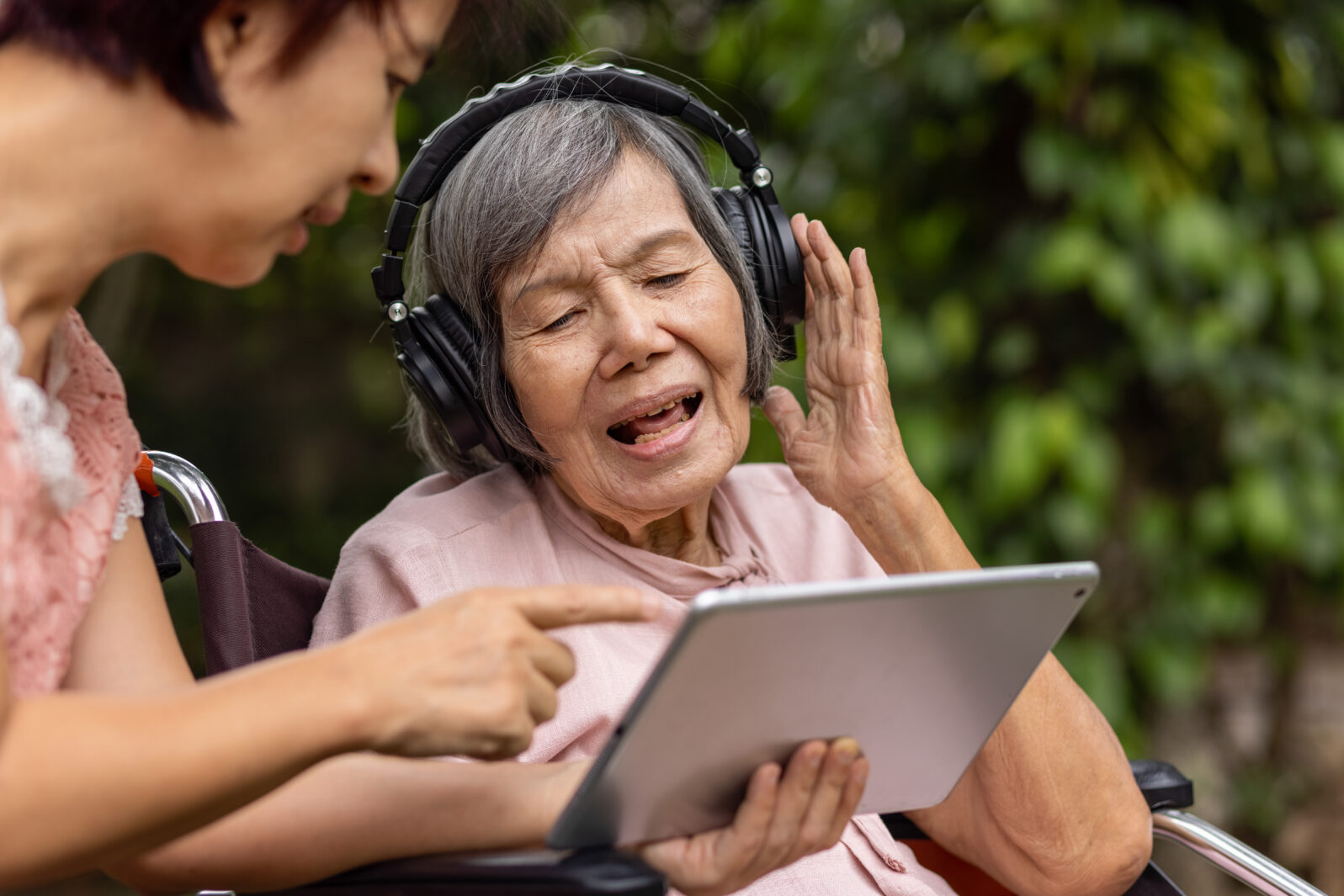 senior woman and daughter listening music with headphone in backyard
