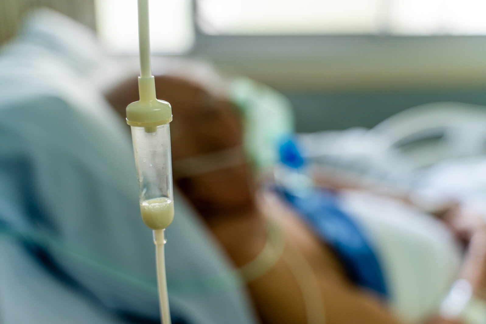 Enteral feeding dropper and a old man patient in the hospital with oxygen mask in the background