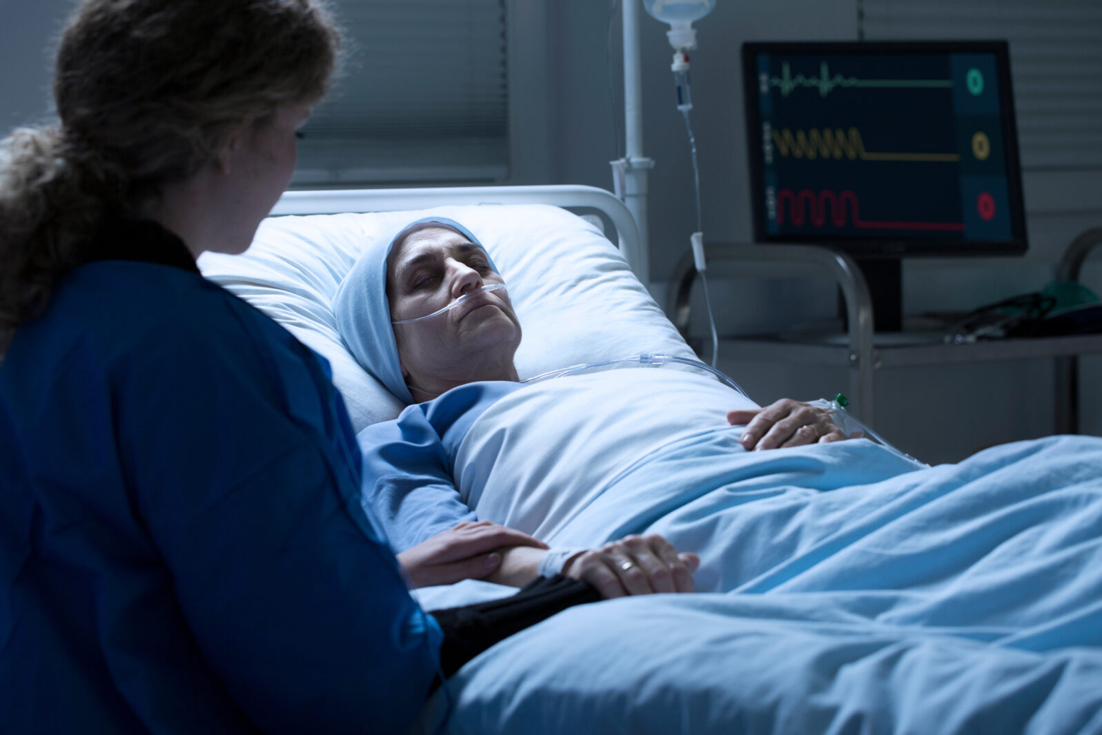Woman holding dying mother's hand