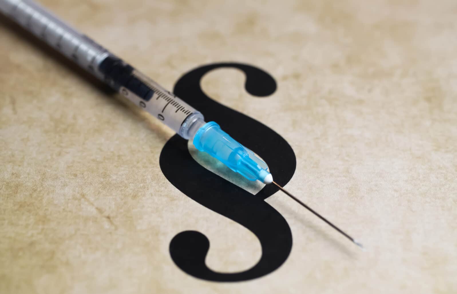 Closeup of paragraph symbol with vaccination injection syringe - euthanasia assisted suicide dying concept