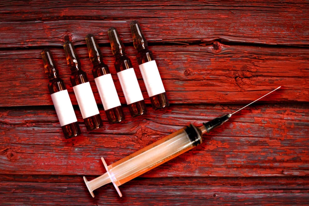 Euthanasia or mercy killing. Malpractice medicine. Syringe with needle and ampules set for assisted death. Bloody red closeup macro. Ethic or criminal debates poster of doctor assisted suicide
