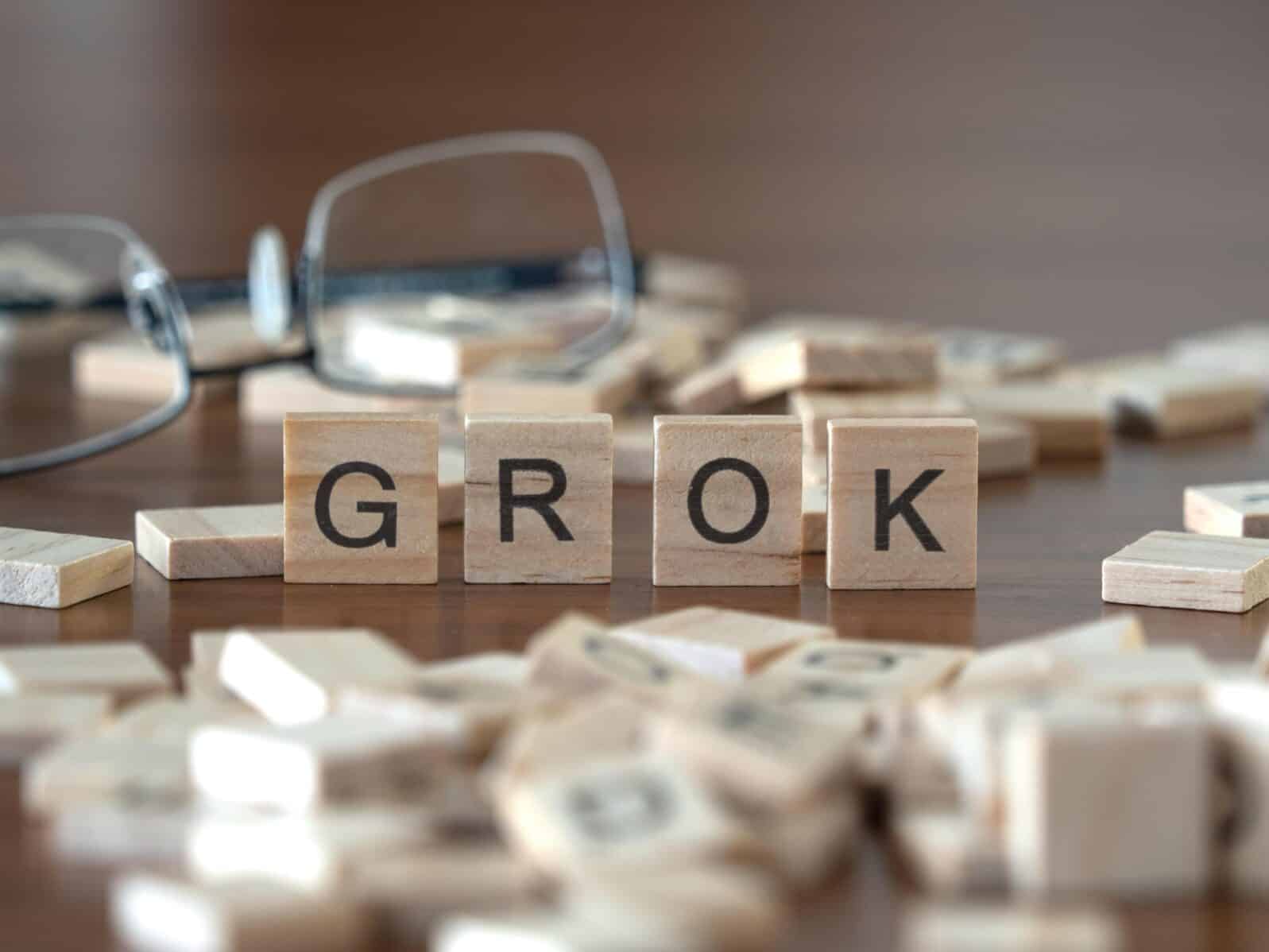 grok word or concept represented by wooden letter tiles on a wooden table with glasses and a book