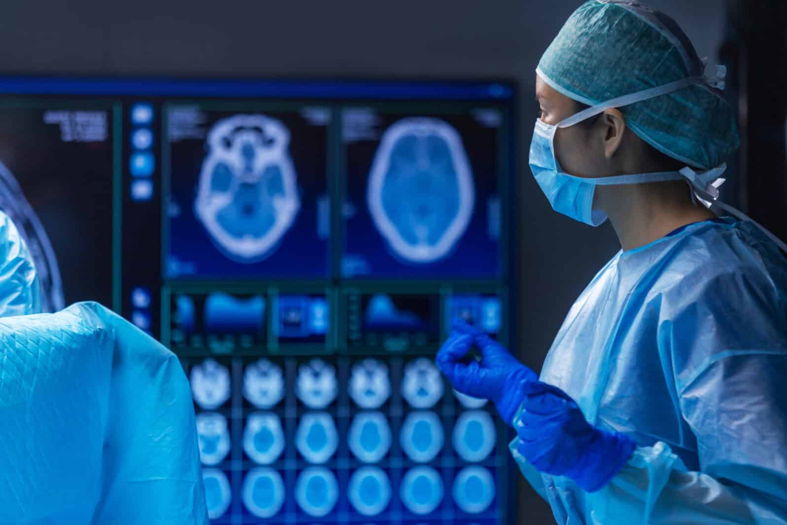Multiracial team of professional medical surgeons performs the surgical operation in a modern hospital. Doctors are working to save the patient. Medicine, health and neurosurgery.