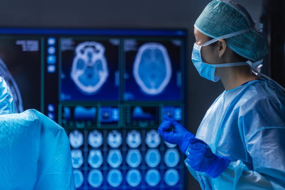 Multiracial team of professional medical surgeons performs the surgical operation in a modern hospital. Doctors are working to save the patient. Medicine, health and neurosurgery.