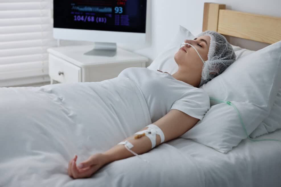 Coma patient. Young woman with intravenous drip in hospital bed