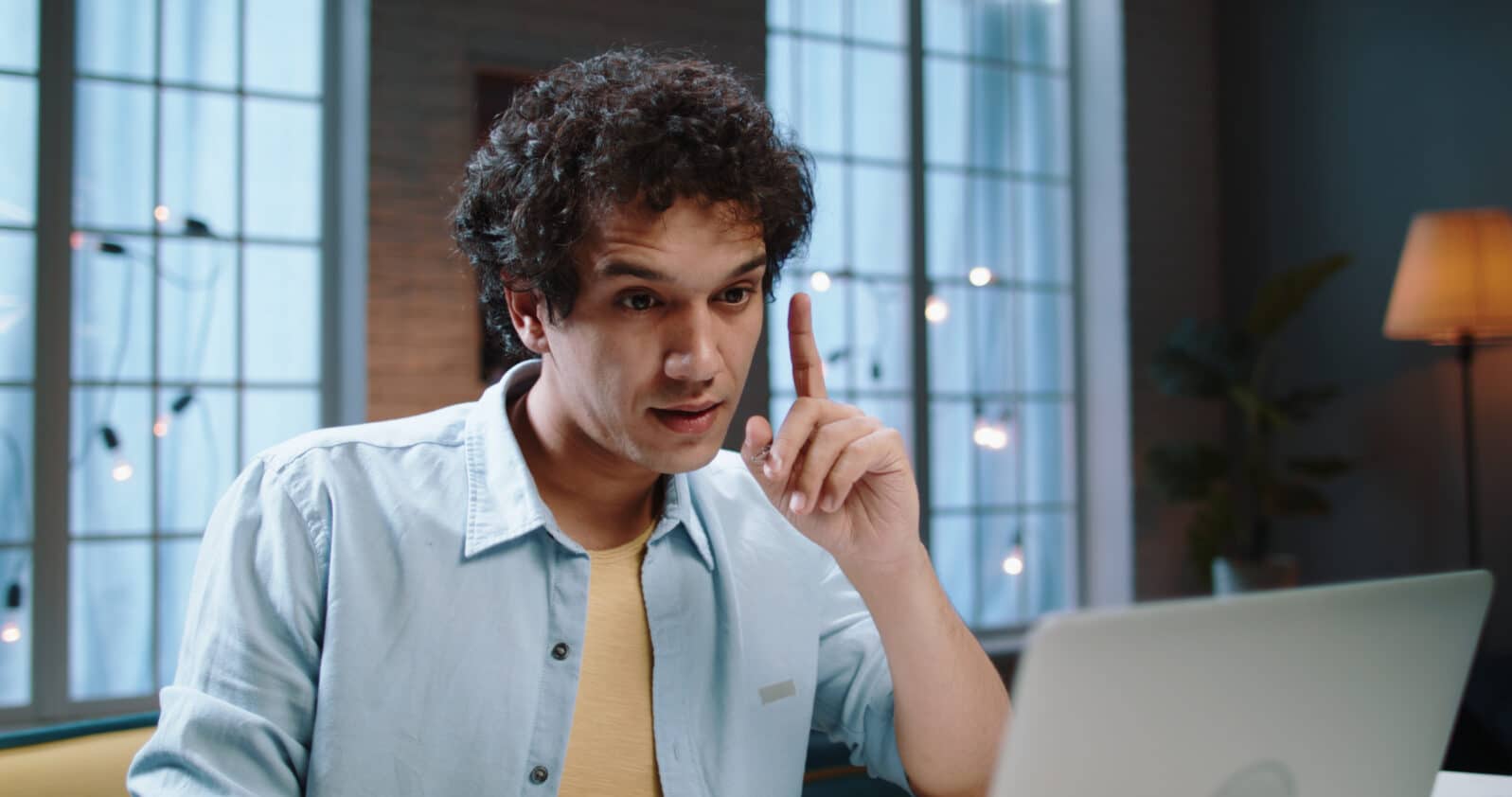 Great Idea Concept. Young Asian businessman Pointing Finger Up. Excited Curly Guy Got Solution To This Problem, Having Aha Moment. Concentrated university student listening to a video lecture.