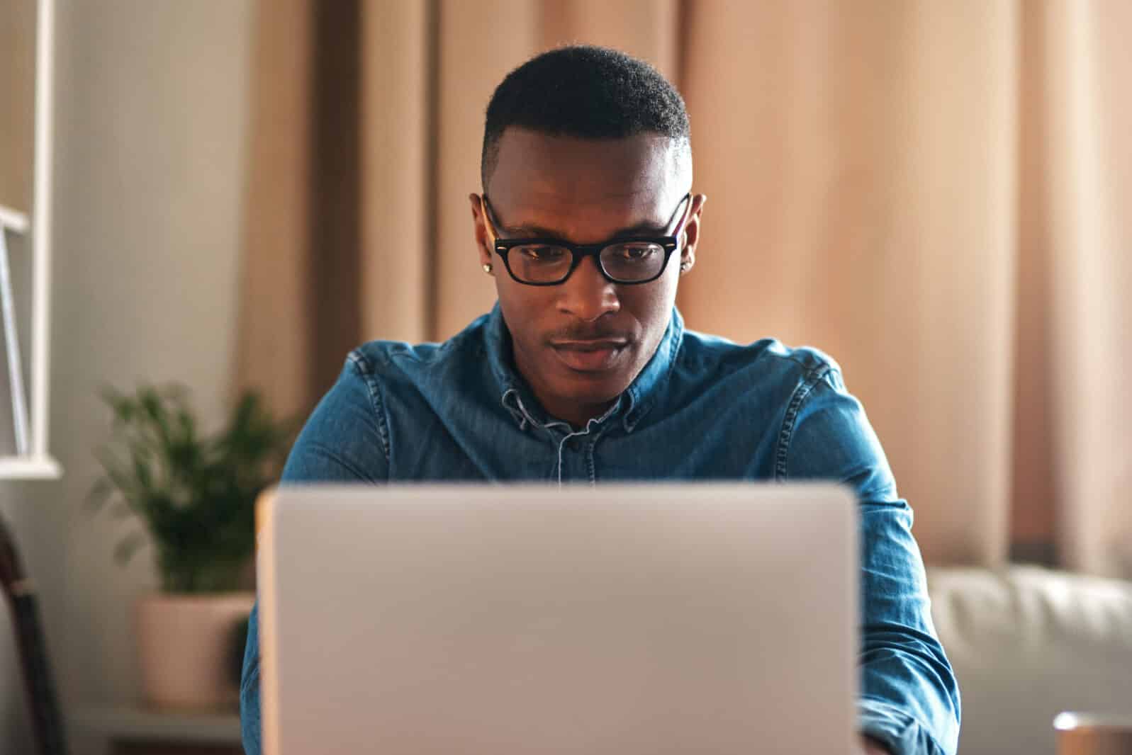 Freelance blogger typing on laptop, thinking of blog post or planning off story vision while working from home living room. Serious, ambitious or inspired writer or entrepreneur working on technology