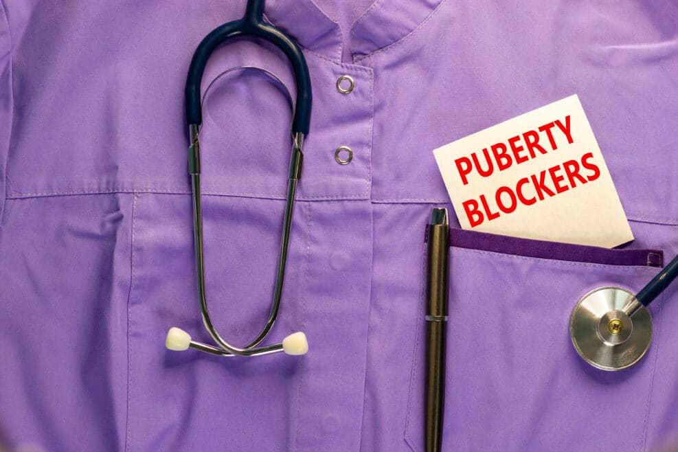 Medical and puberty blockers symbol. Medical uniform, white card with words 'puberty blockers'. Beautiful white background. Copy space. Medical and puberty blockers concept.
