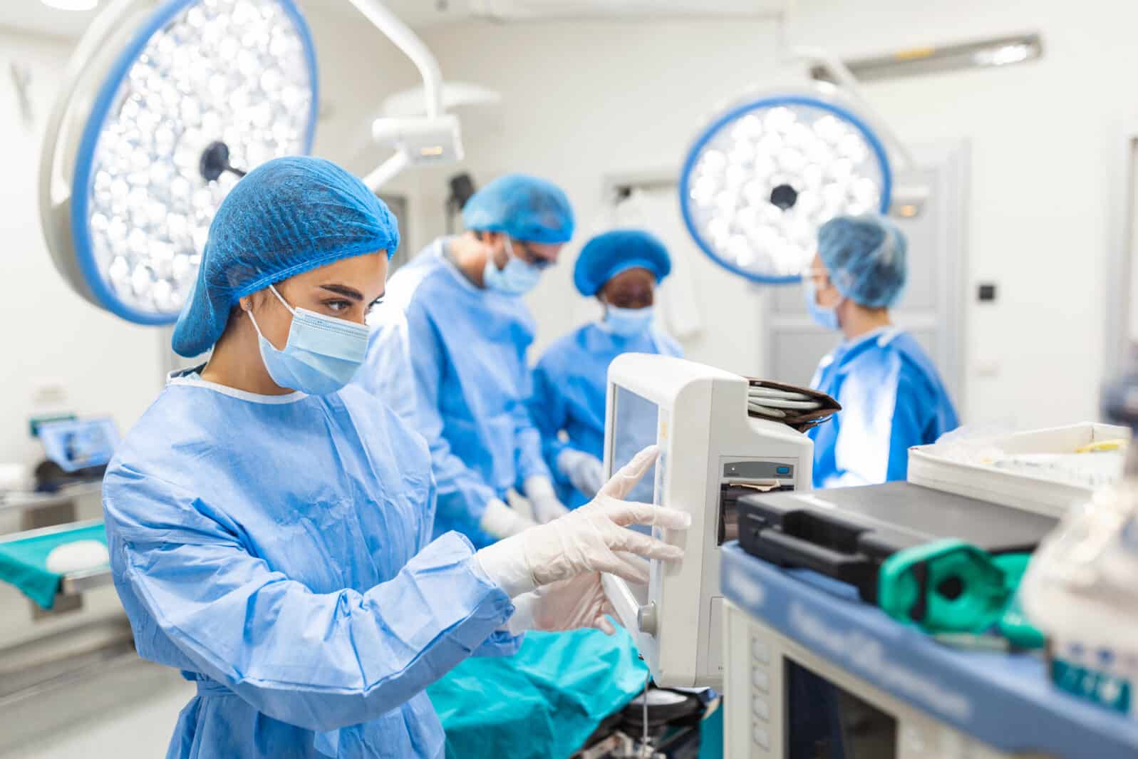 Anesthesiologist keeping track of vital functions of the body during cardiac surgery. Surgeon looking at medical monitor during surgery. Doctor checking monitor for patient health status.