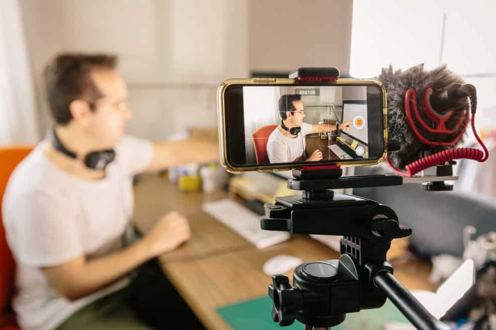 Boy recording with his mobile phone a video for social networks. Use an external microphone to make it easier to hear. Youtuber