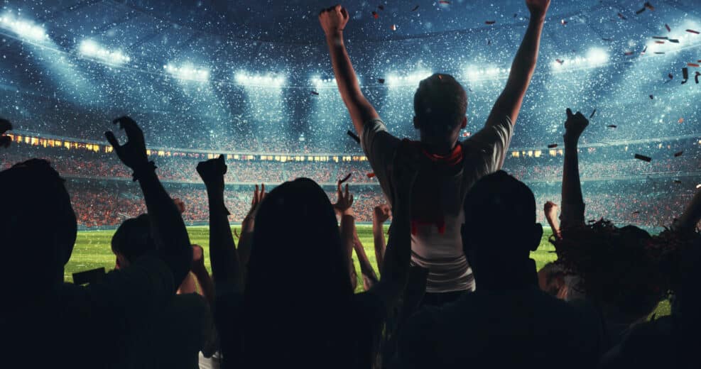 Fans celebrating the success of their favorite sports team on the stands of the professional stadium while it's snowing