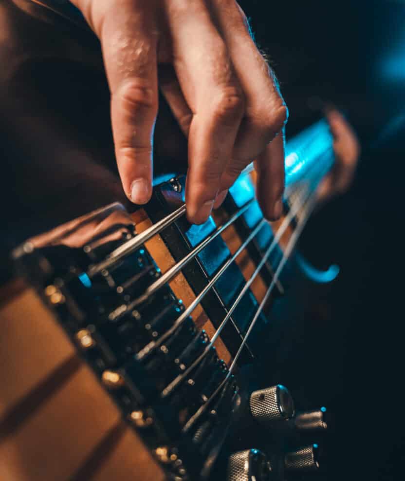 Closeup of male fingers playing 5 stringed electric bass guitar